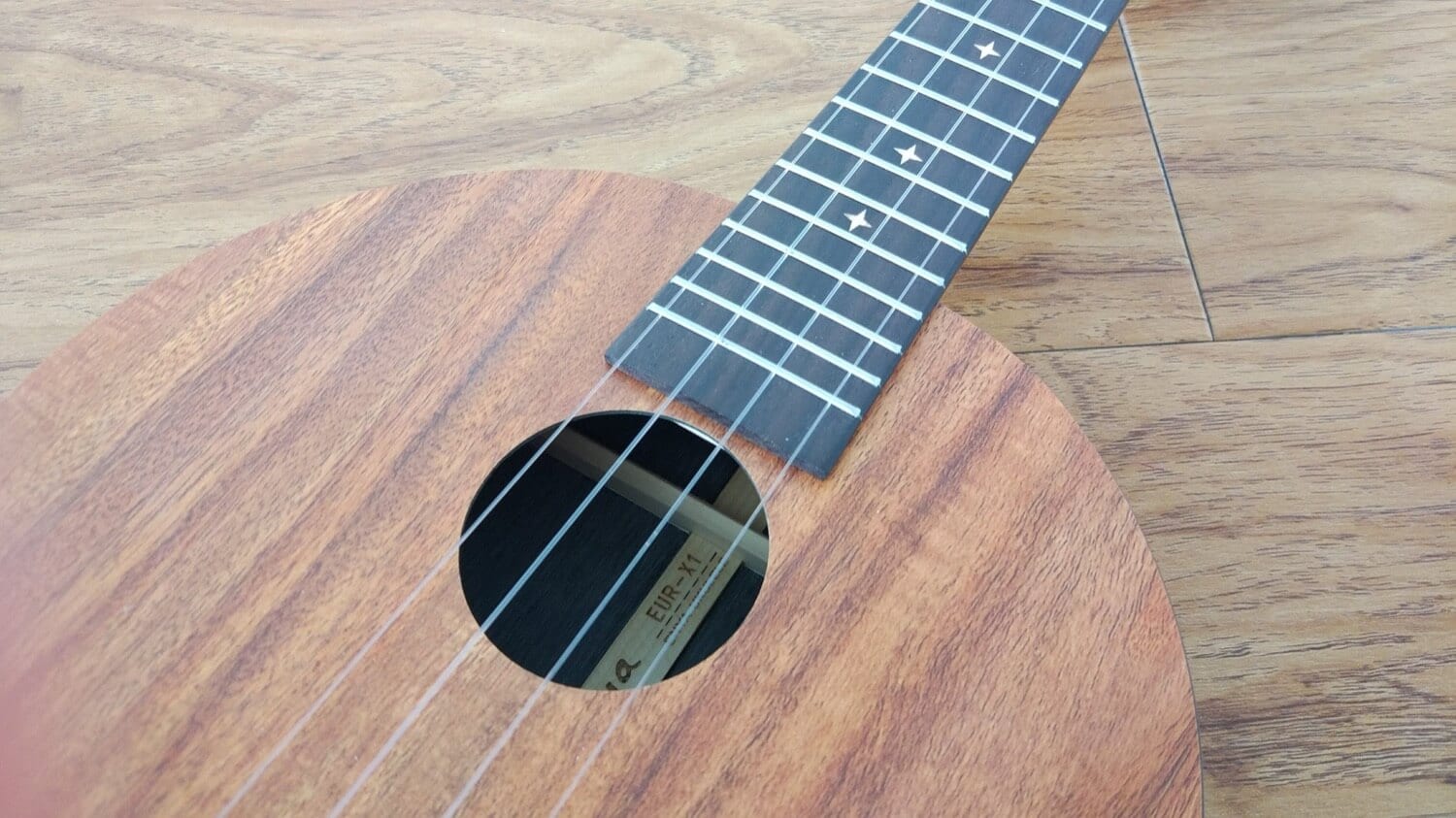 Nahaufnahme einer runden Ukulele aus Holz mit Griffbrett und Schallloch